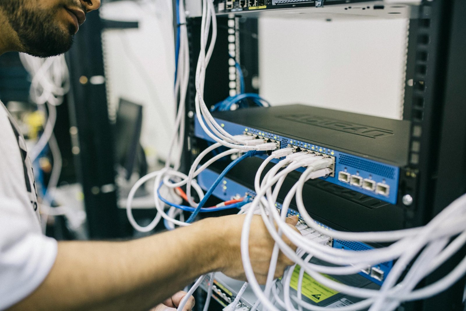Technician connecting network cables to a rack-mounted server or network switch inside a data center.
