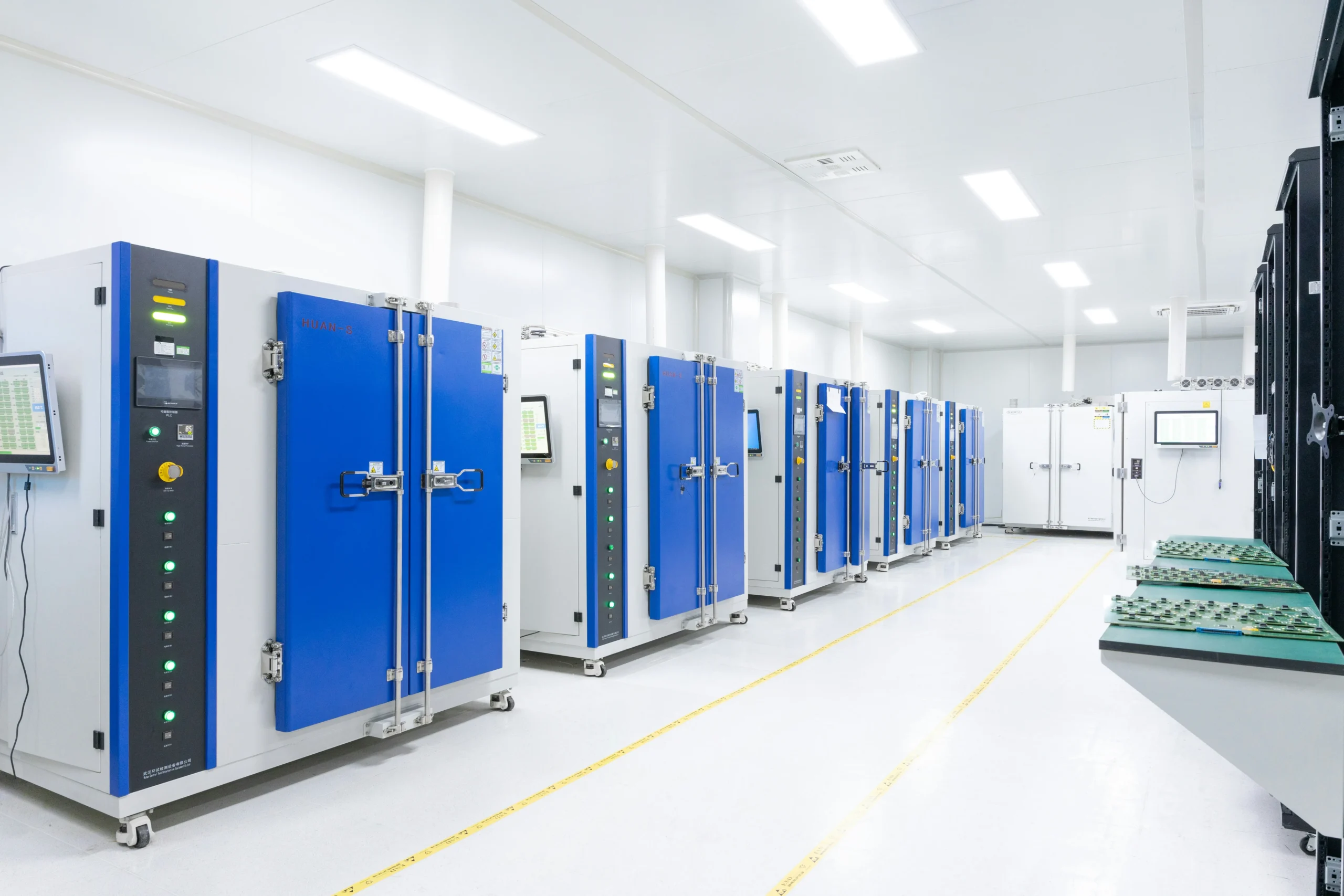 Bright, clean data center room with multiple blue server cabinets, control panels, and monitoring screens along the walls.