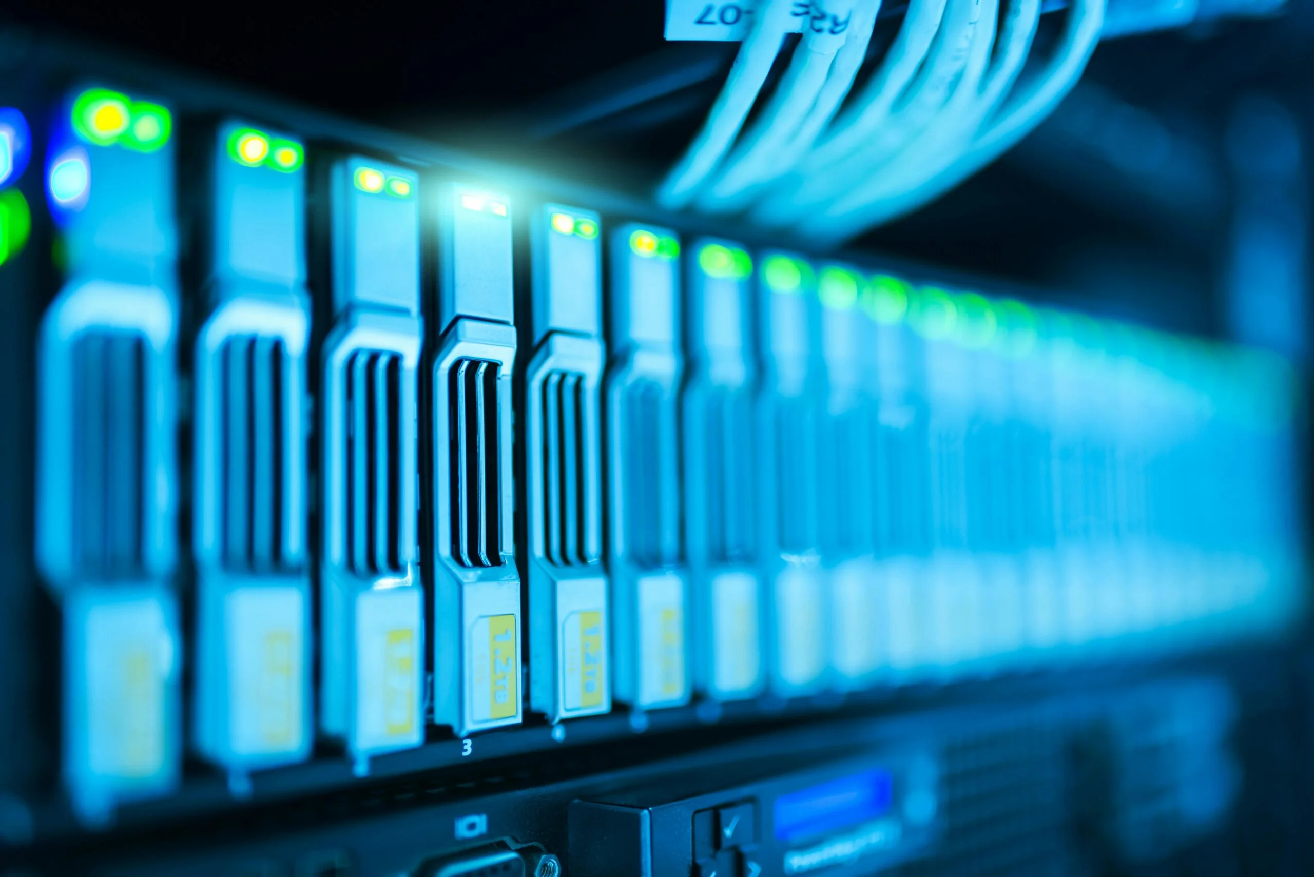 Close-up of server rack with glowing LED lights and connected network cables in a data center.