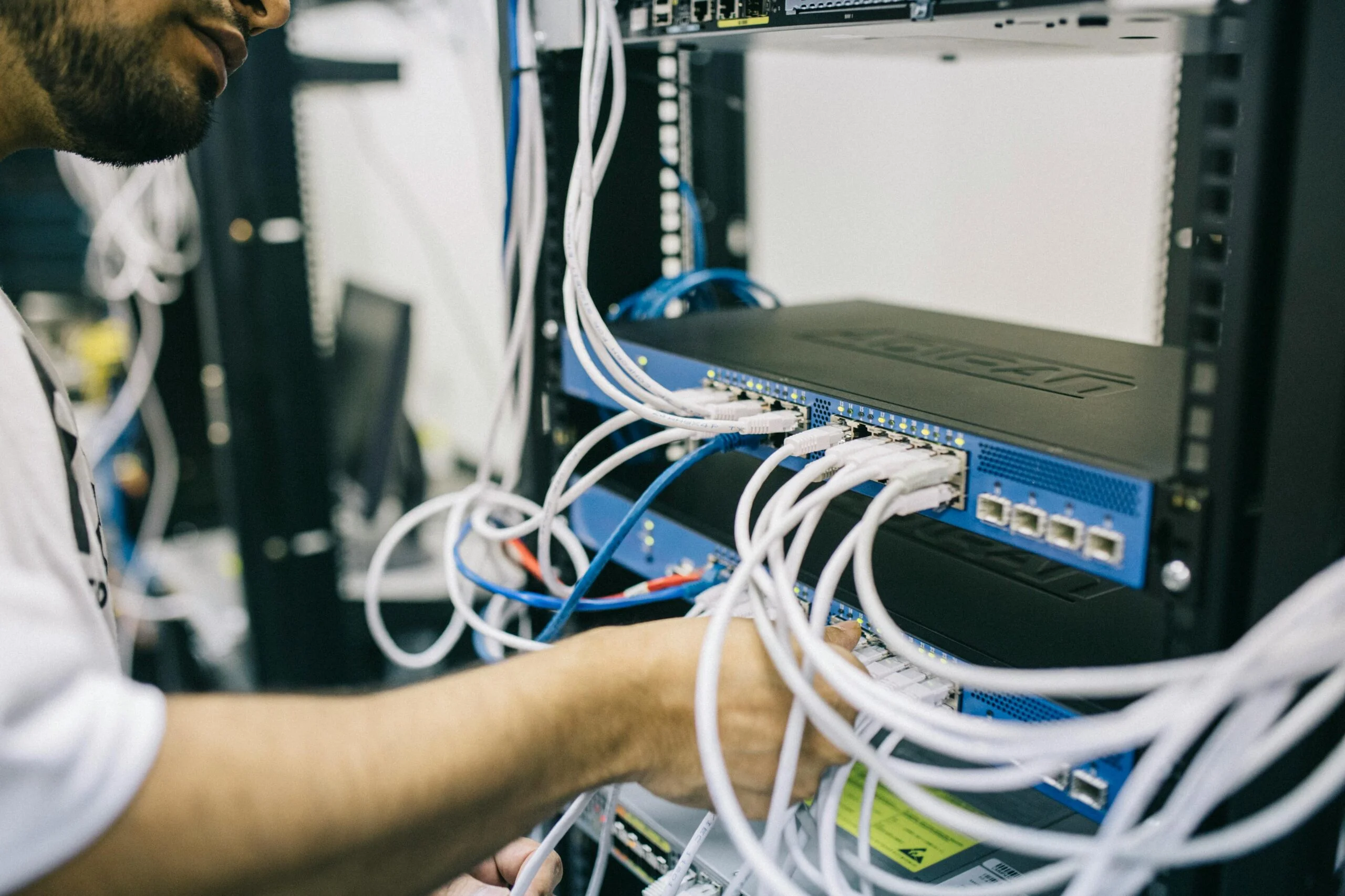 Technician connecting network cables to a rack-mounted server or network switch inside a data center.